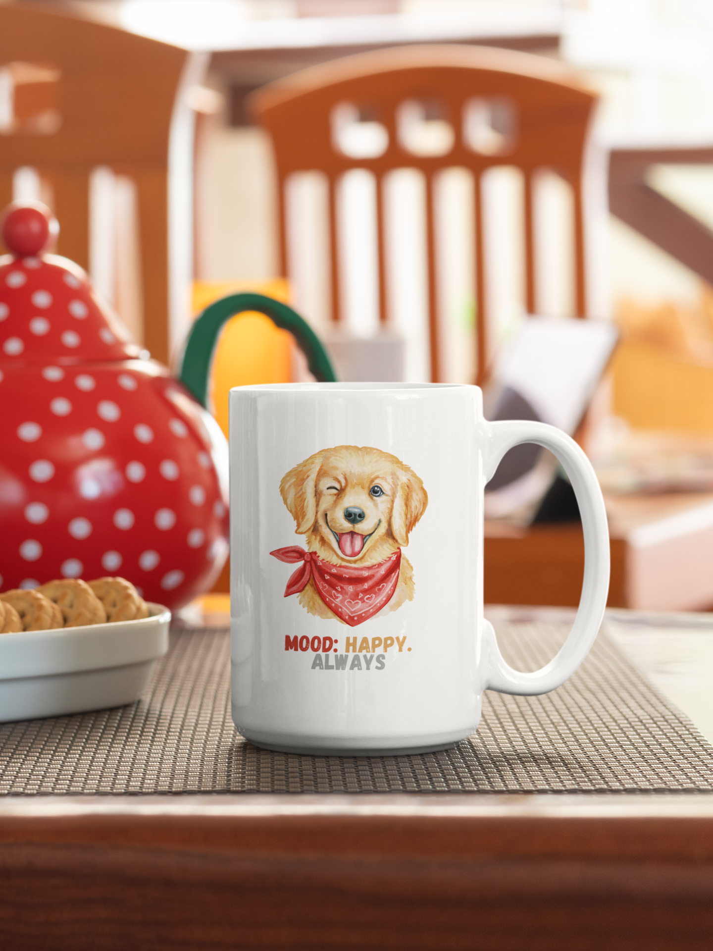 White coffee mug with golden retriever graphic and mood happy always slogan next to biscuits and a colored teapot