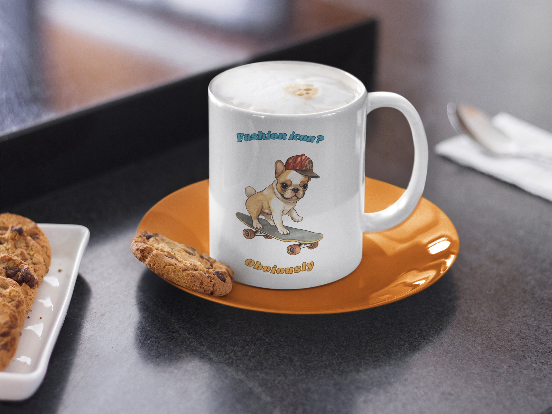 White coffee mug with French Bulldog graphic and fashion icon obviously slogan next to chocolate chip cookies