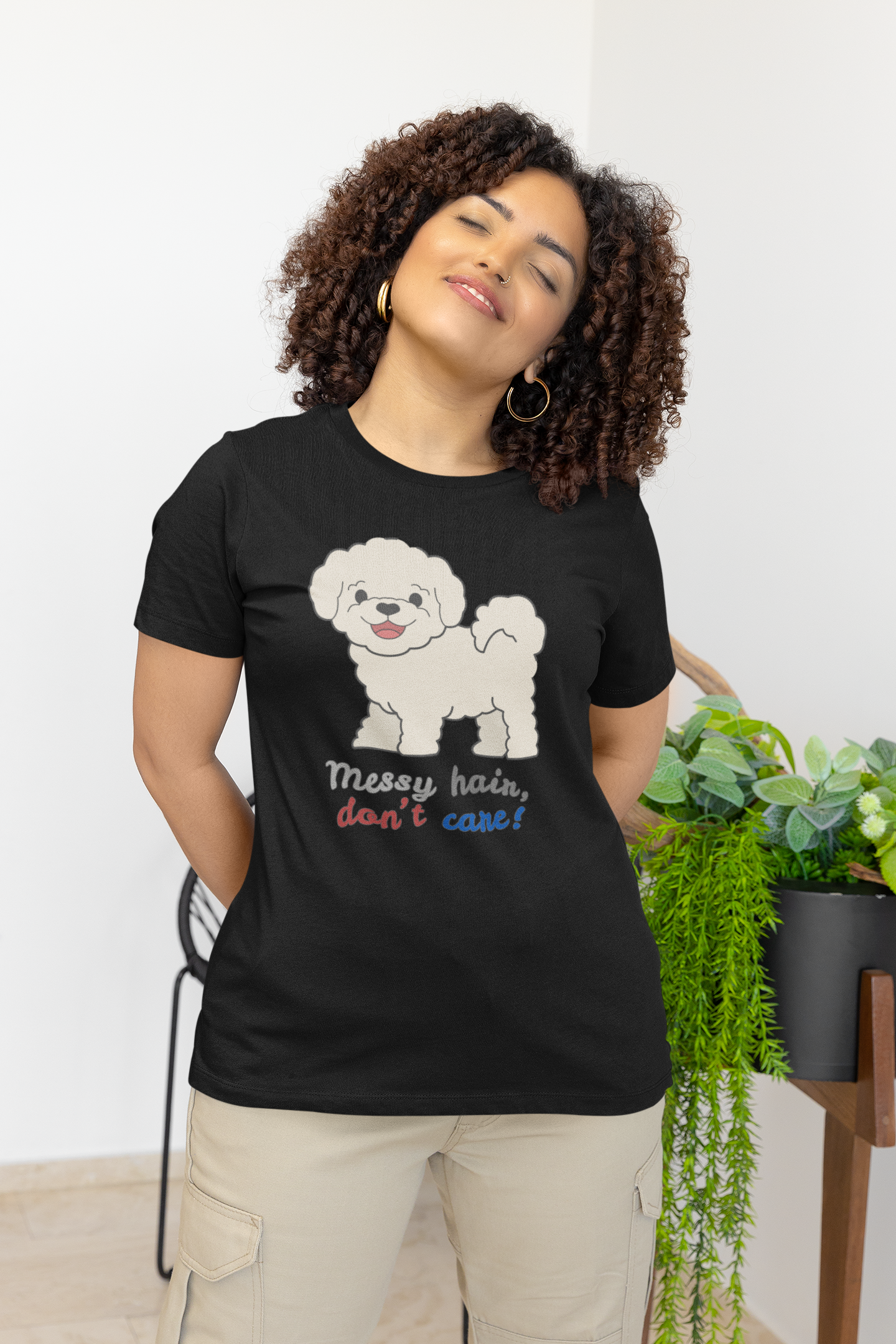 Curly haired woman wearing black Bella Canvas crew neck t shirt with bichon dog graphic and messy hair don’t care slogan