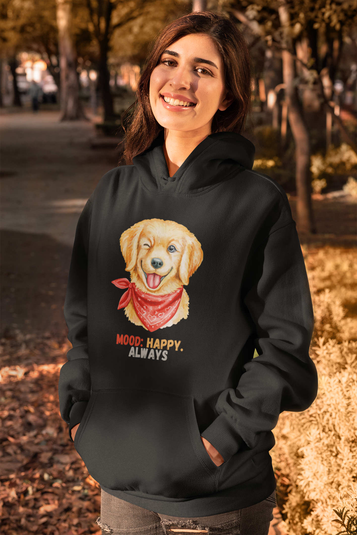Woman wearing black pullover hoodie with labrador retriever graphic and mood happy always slogan in a cozy fall setting