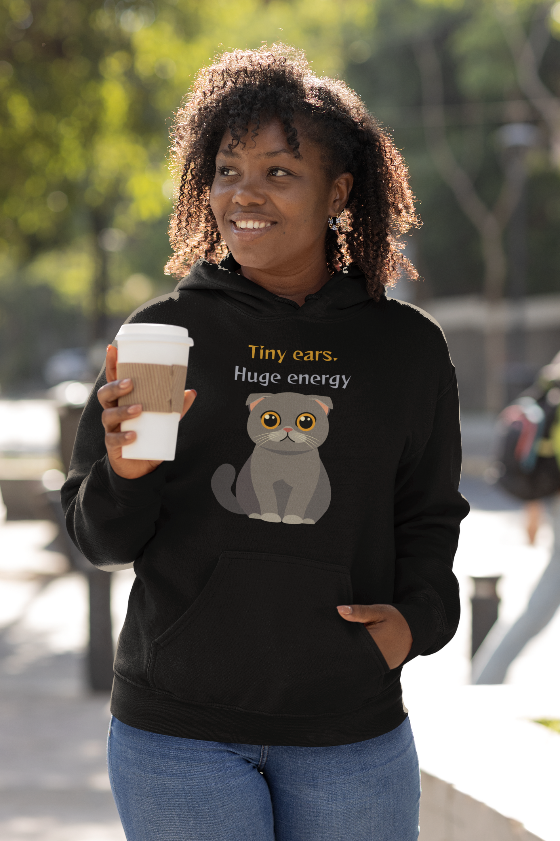 Woman with curly hair wearing white Gildan pullover hoodie with Scottish Fold cat graphic and tiny ears huge energy slogan