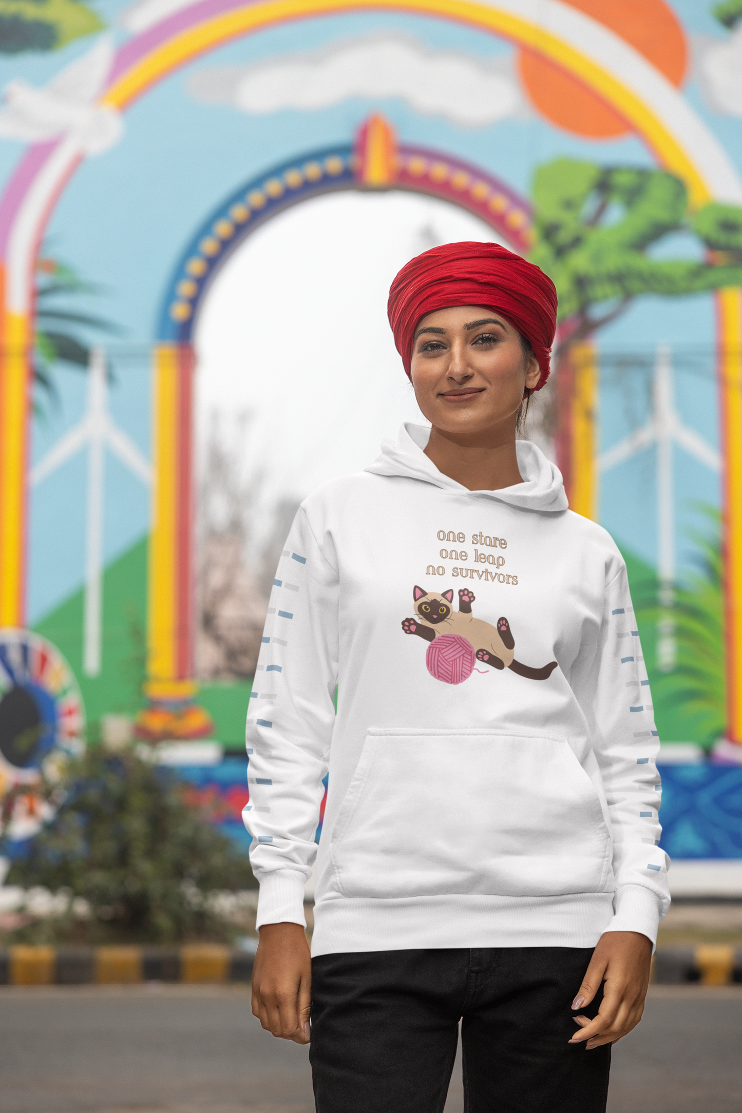 Smiling woman wearing a turban and white hoodie with Siamese cat graphic and one stare one leap no survivors slogan