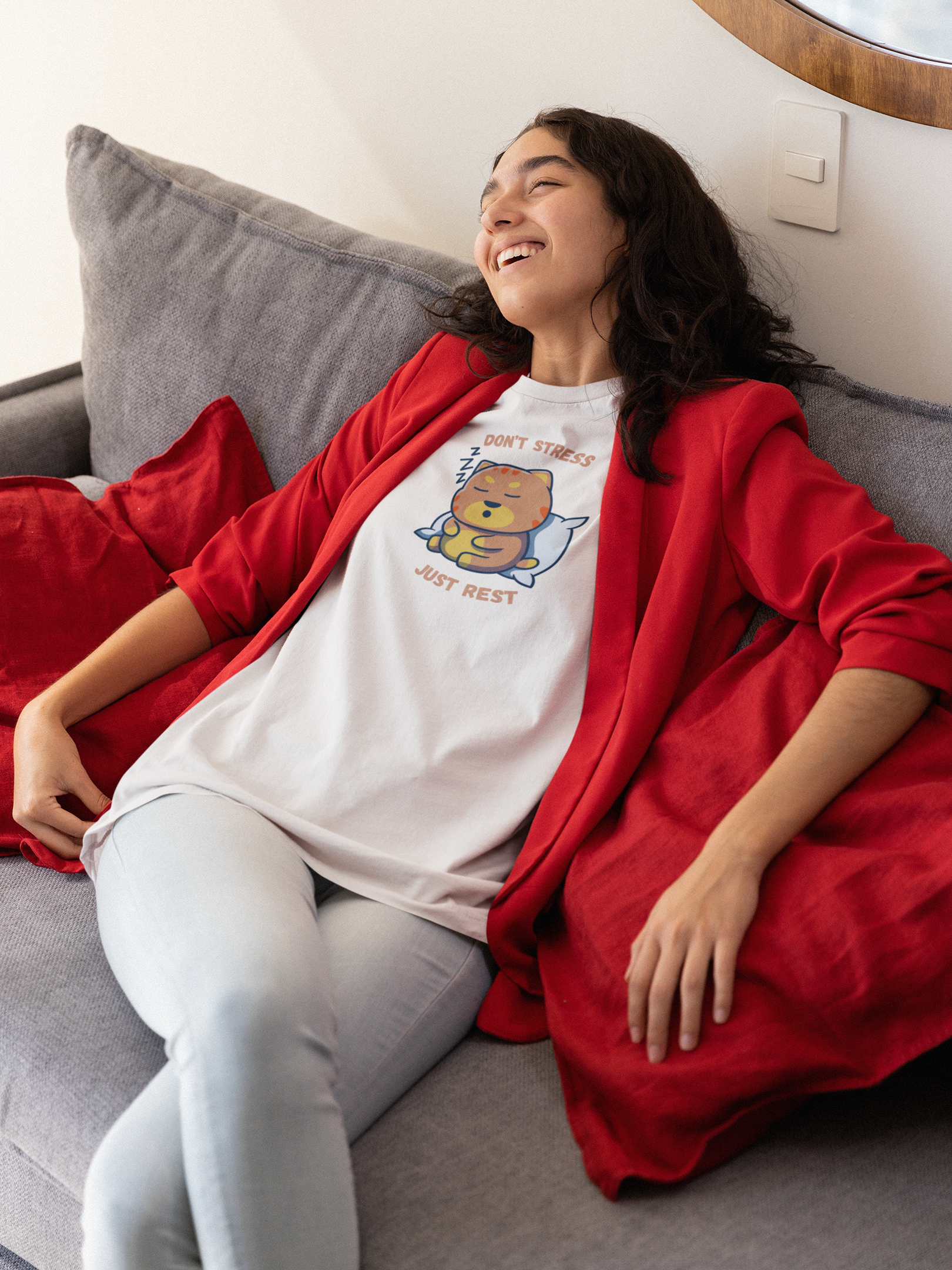 Young woman resting on couch wearing white t-shirt with sleepy cat graphic and don’t stress just rest slogan